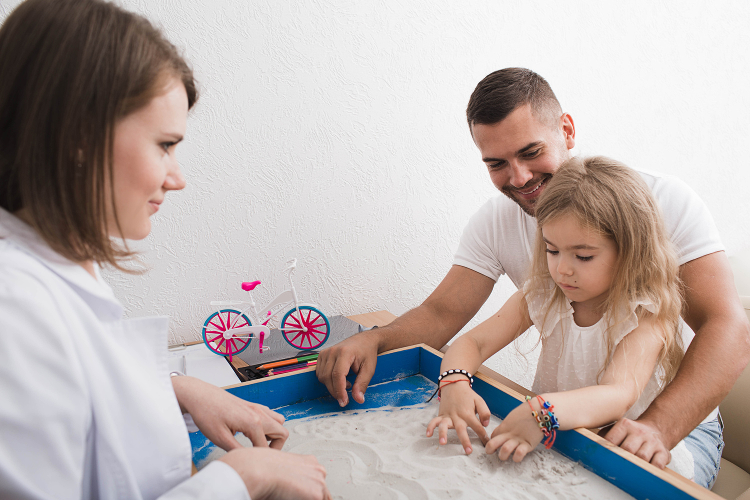 Sand therapy as a way of mental therapy and treatment of children. psychiatrist, doing sand therapy with child and her parent